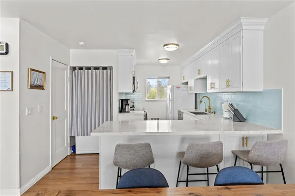 a kitchen with stainless steel appliances granite countertop a dining table chairs and a refrigerator