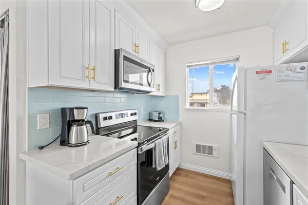 a kitchen with stainless steel appliances granite countertop a refrigerator a stove a sink and white cabinets