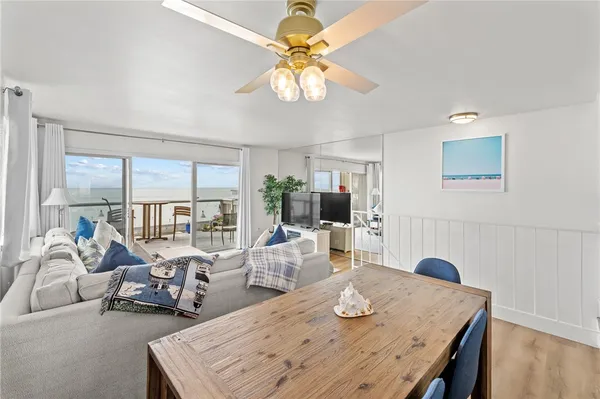 a view of a dining room with furniture a chandelier and large windows