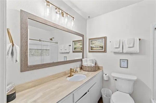 a bathroom with a granite countertop toilet sink and mirror