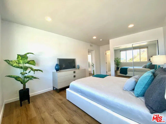 a bedroom with a large bed and a potted plant