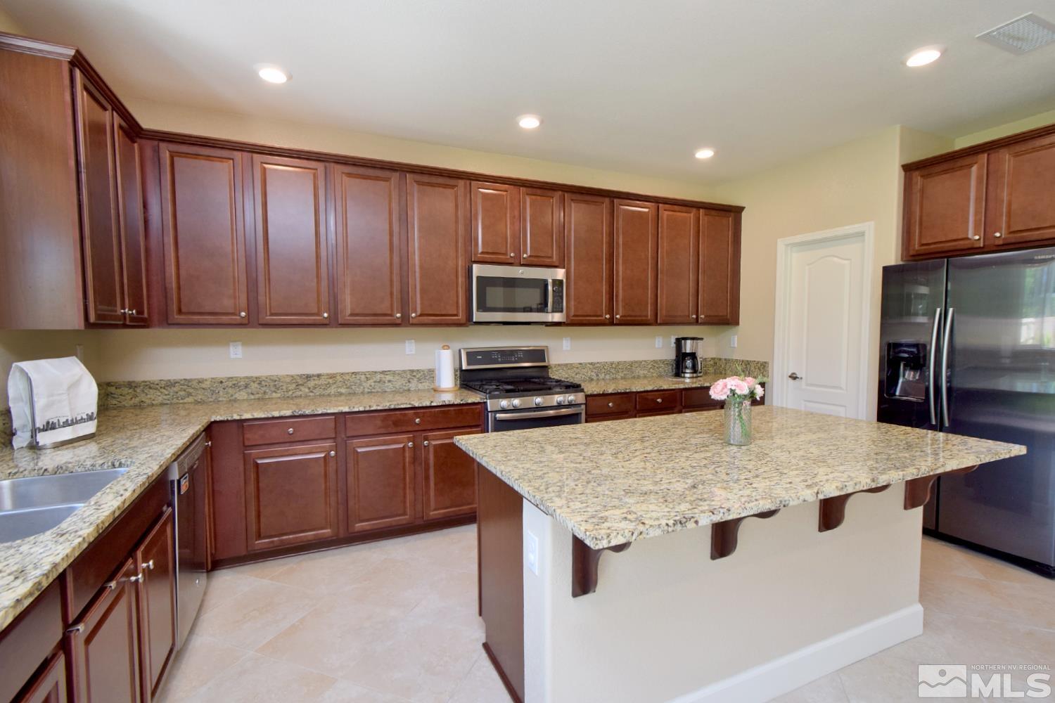 9729 Pachuca Drive Reno, NV 89521 - Photo 8 of 40 a kitchen with kitchen island granite countertop wooden cabinets a sink and a stove