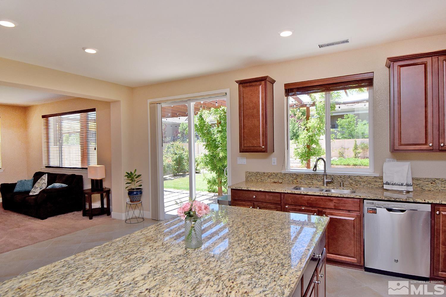 9729 Pachuca Drive Reno, NV 89521 - Photo 10 of 40 a kitchen with granite countertop a stove a sink a dining table and chairs