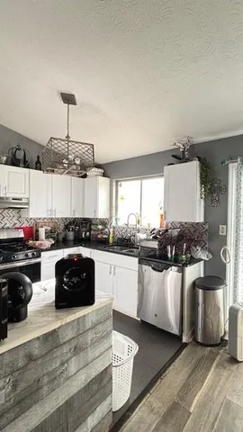 a kitchen with stainless steel appliances a stove a sink and white cabinets