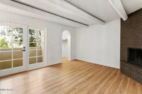 an empty room with wooden floor fireplace and windows