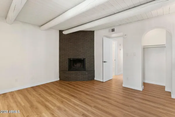 a view of empty room with wooden floor and fireplace