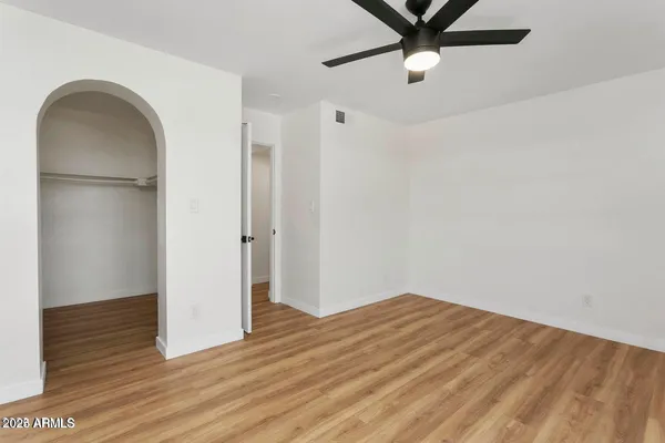 a view of empty room with wooden floor and fan