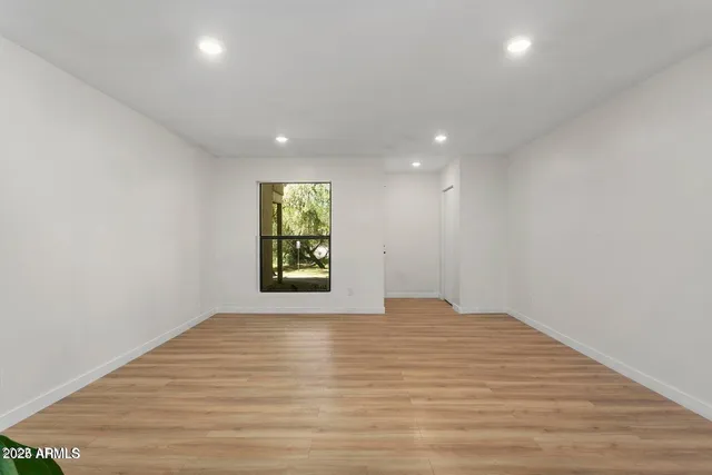 a view of an empty room with window and wooden floor