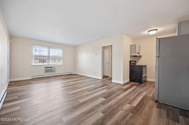 a view of empty room with wooden floor and window