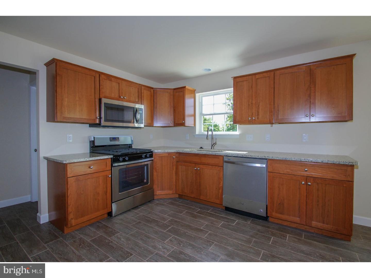 4520 Sefranka Road Temple, PA 19560 - Photo 7 of 23 a kitchen with granite countertop a stove top oven a sink dishwasher a microwave oven with cabinets and wooden floor