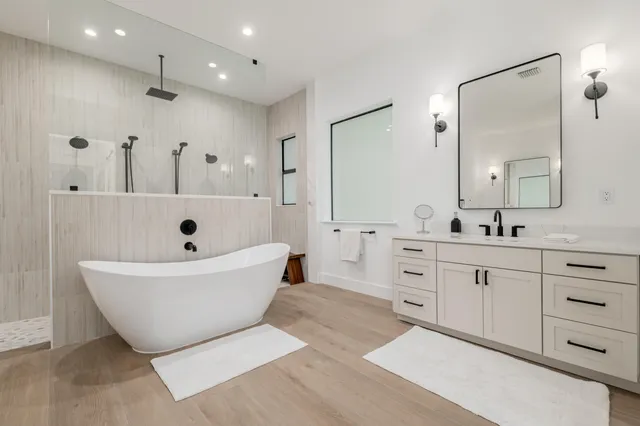 a spacious bathroom with double vanity a mirror a bathtub and shower