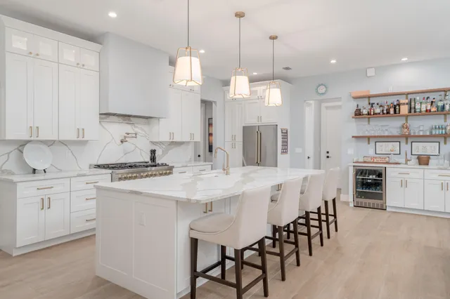 a kitchen with stainless steel appliances kitchen island a table chairs and a refrigerator