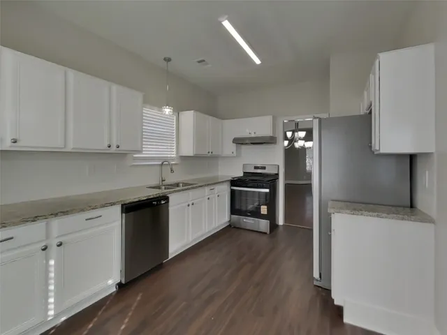 a kitchen with granite countertop white cabinets and stainless steel appliances