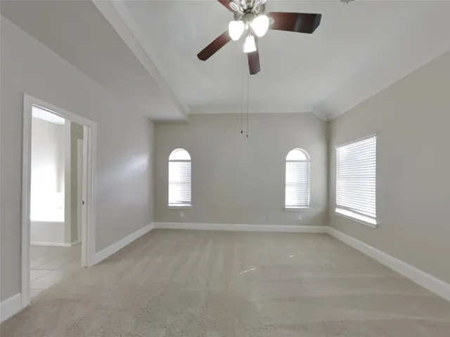 an empty room with windows and chandelier fan