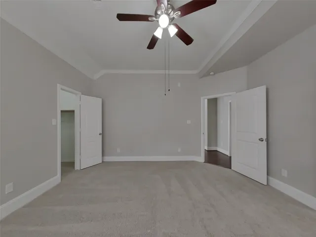 a view of an empty room and chandelier fan