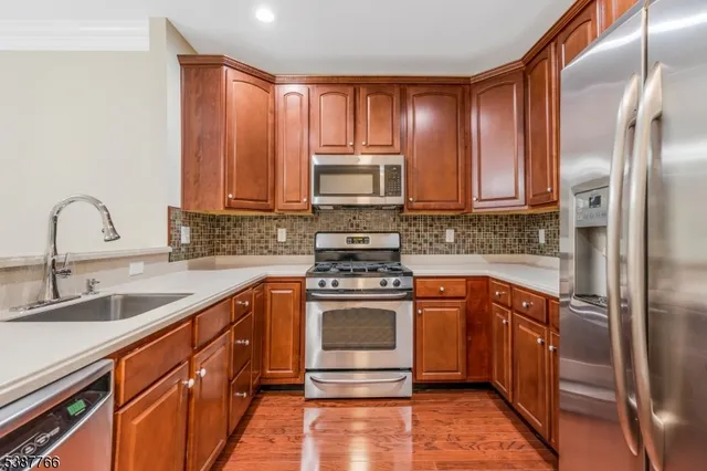 a kitchen with stainless steel appliances granite countertop a stove a sink and a refrigerator