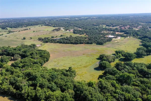 an aerial view of ocean and residential houses with outdoor space and trees