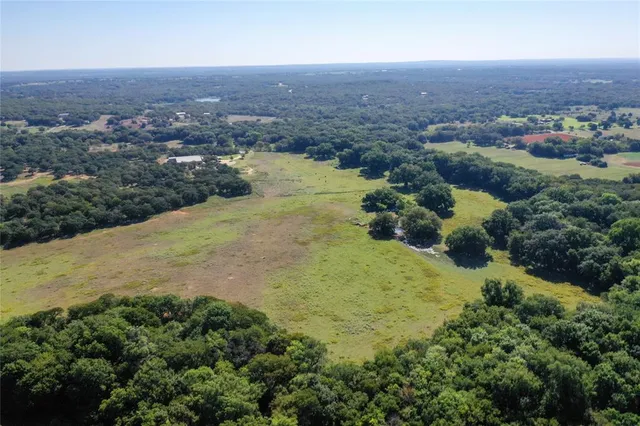an aerial view of residential houses with outdoor space and trees