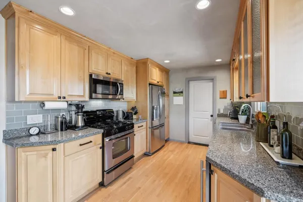 a kitchen with stainless steel appliances granite countertop a refrigerator a stove top oven a sink and dishwasher