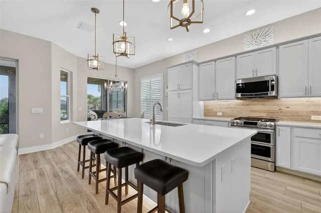 a kitchen with kitchen island granite countertop a stove a sink a dining table and chairs with wooden floor