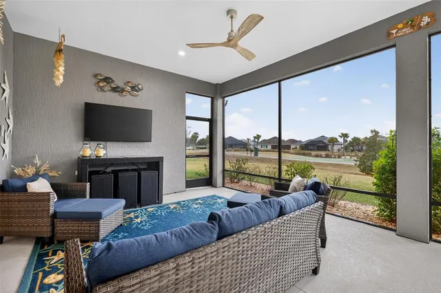 a living room with furniture a flat screen tv and a floor to ceiling window