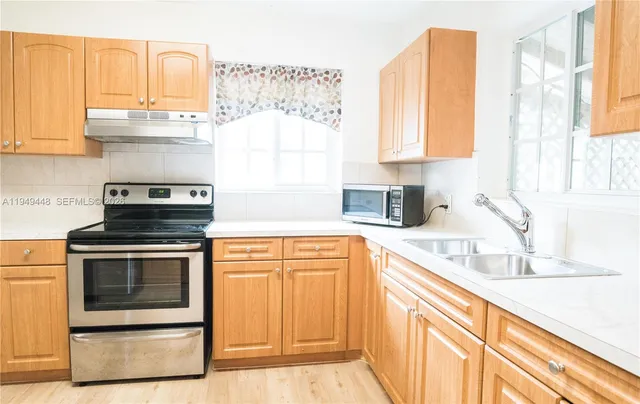 a kitchen with stainless steel appliances granite countertop a stove a sink and a microwave