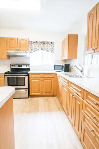 a large kitchen with stainless steel appliances granite countertop a stove a sink and a microwave