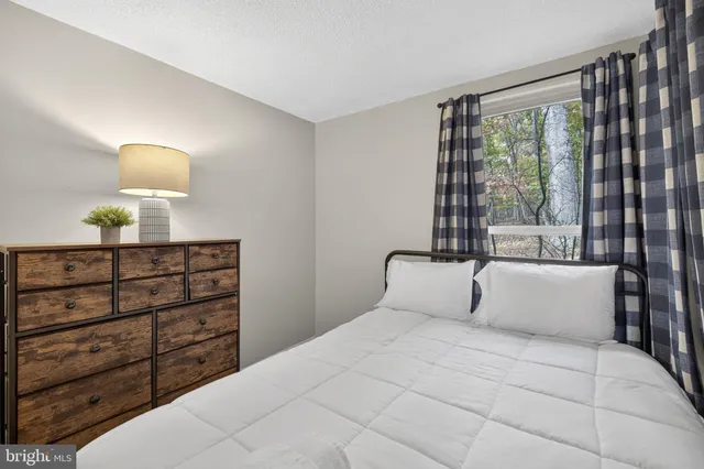 a bedroom with a bed a dresser and a window