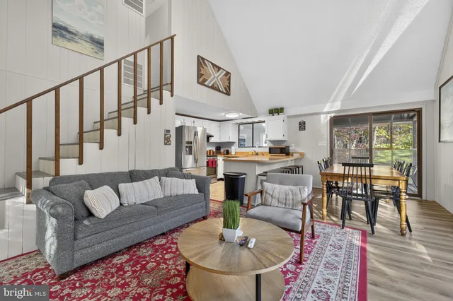 a living room with furniture and a dining table with wooden floor