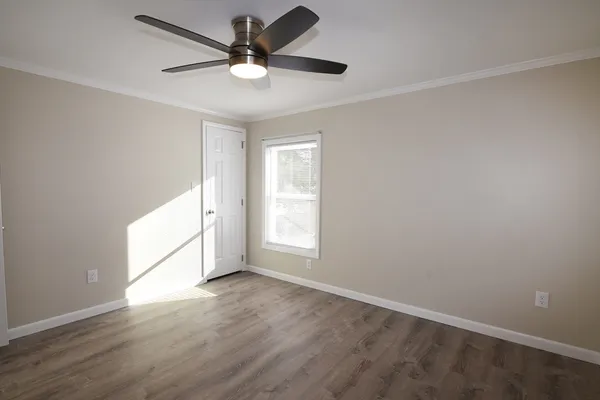 an empty room with wooden floor and windows