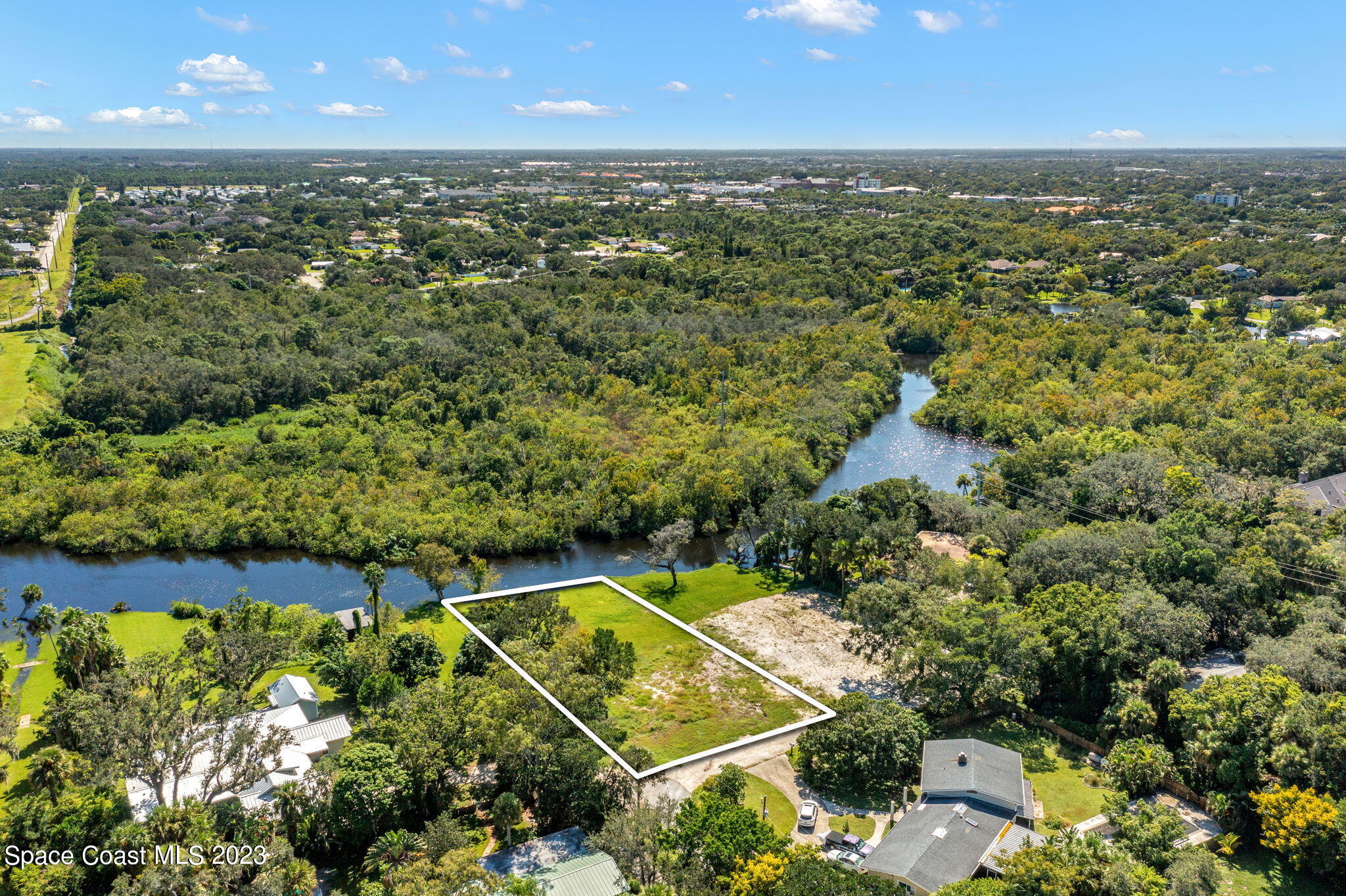 an aerial view of a residential houses with outdoor space and trees