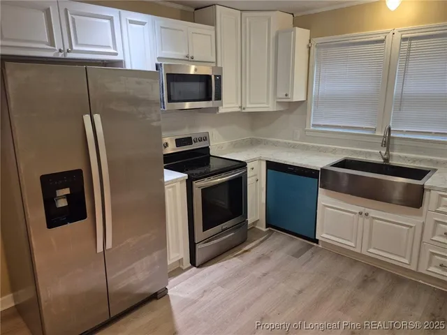a kitchen with stainless steel appliances granite countertop a refrigerator a stove a sink and white cabinets