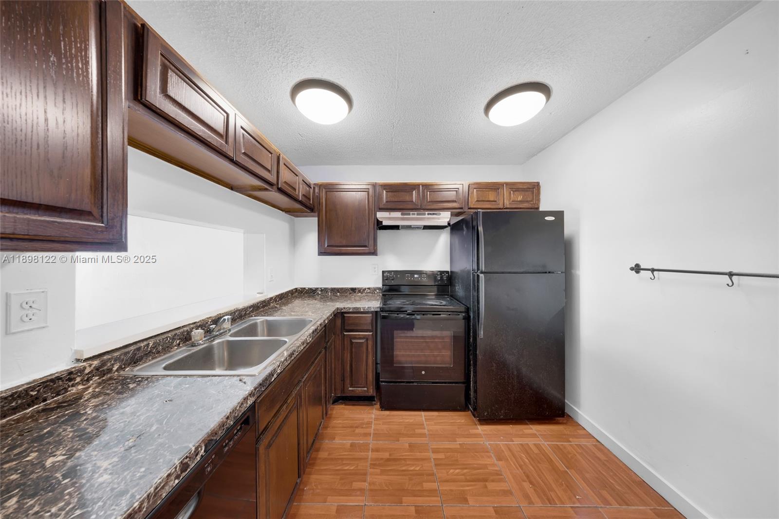 492 Northwest 165th Street, Unit C512 Miami, FL 33169 - Photo 10 of 27 a kitchen with granite countertop a refrigerator and a sink