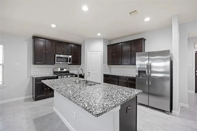 a kitchen with kitchen island granite countertop a sink refrigerator and microwave