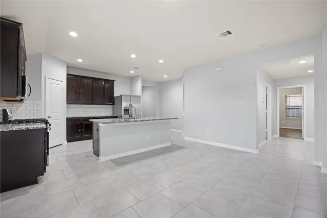 a view of kitchen with kitchen island stainless steel appliances refrigerator stove microwave and sink