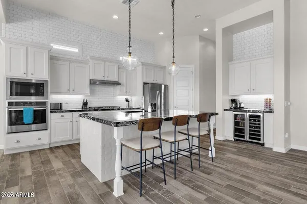 a kitchen with stainless steel appliances kitchen island granite countertop a table chairs sink and cabinets