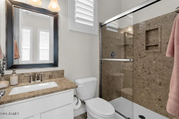 a bathroom with a granite countertop sink a toilet and shower