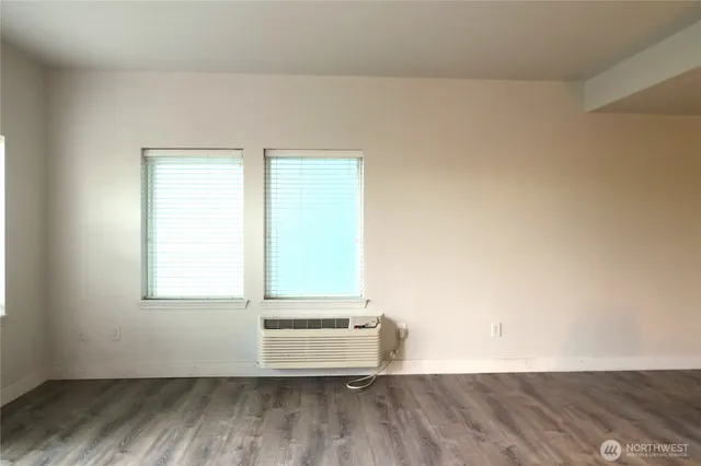 an empty room with wooden floor and windows