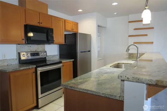 a kitchen with stainless steel appliances granite countertop a sink a microwave a refrigerator and a stove