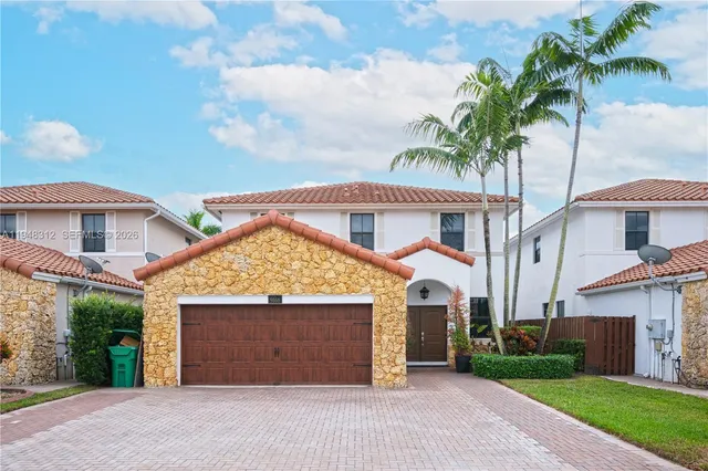 a front view of a house with a garden and garage