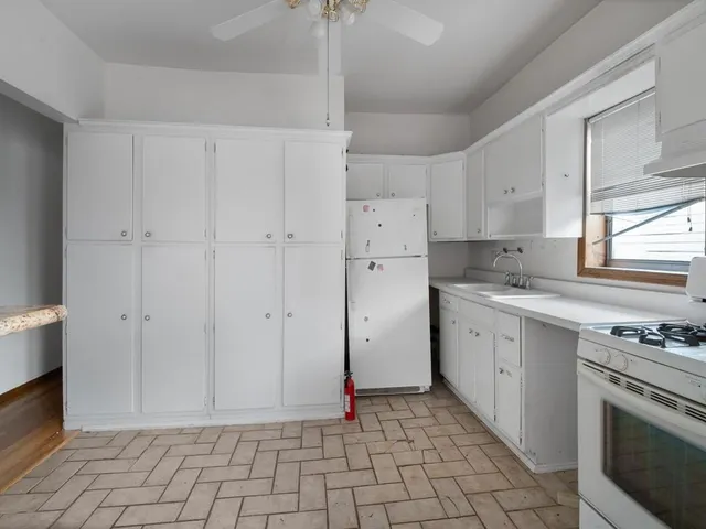 a kitchen with white cabinets and appliances