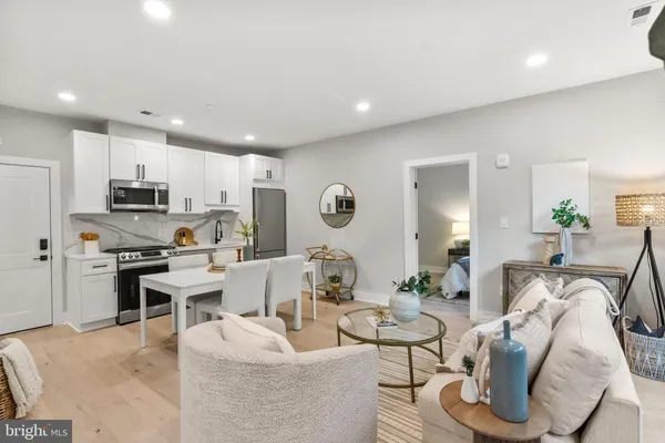 a living room with furniture kitchen view and a wooden floor