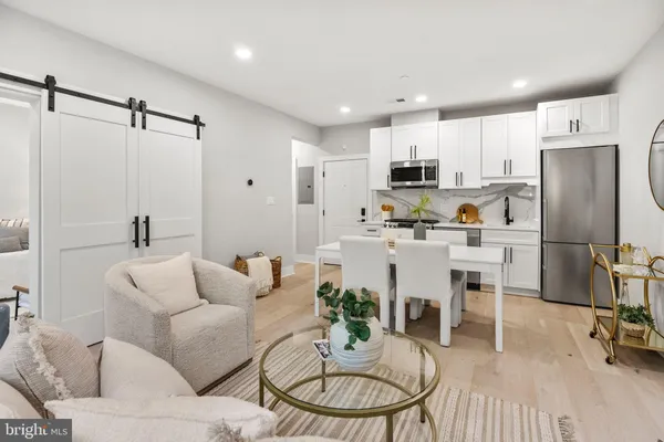 a living room with furniture a refrigerator and kitchen view