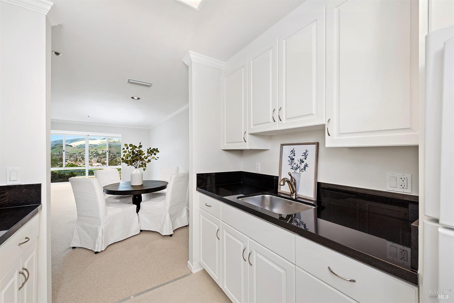 a kitchen with granite countertop a sink and white cabinets