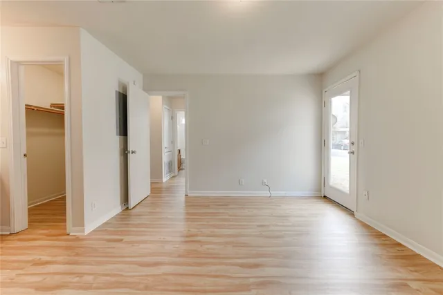 a view of an empty room with wooden floor and a window