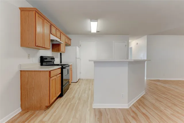 a kitchen with stainless steel appliances granite countertop a refrigerator a stove and a wooden floors