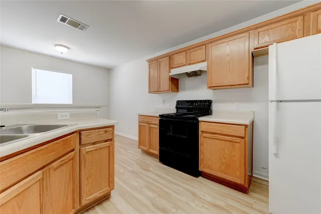 a kitchen with granite countertop wooden cabinets and a stove top oven