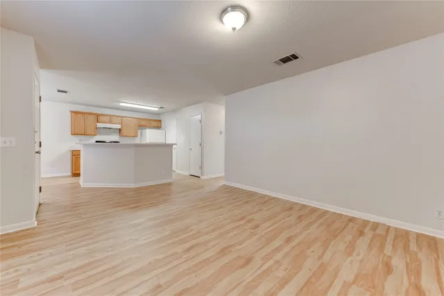 a view of empty room with wooden floor and window