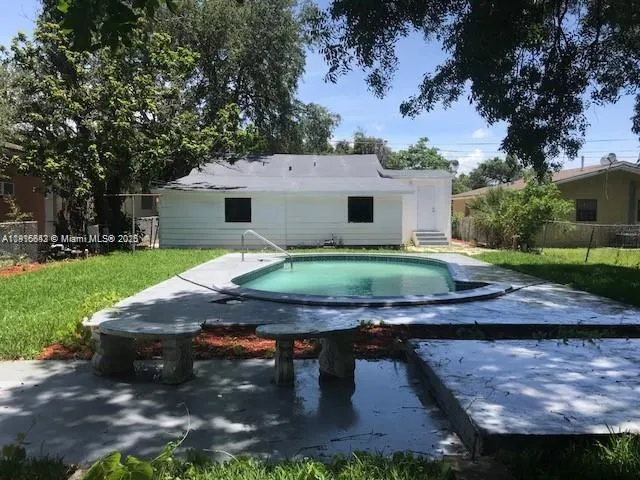 a view of a wooden house with large trees and a big yard
