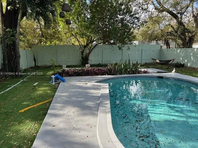 a view of backyard with swimming pool and green space